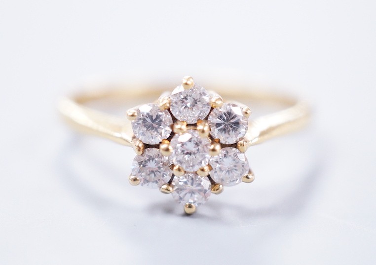 A modern 18ct gold and seven stone diamond set flower head cluster ring, size N/O, gross weight 2.9 grams